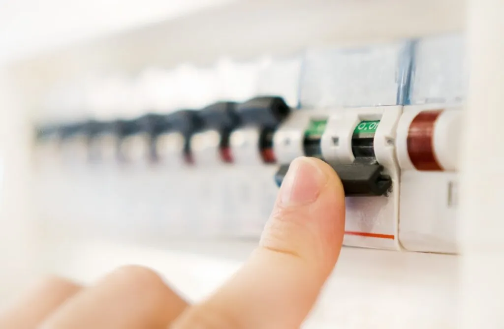 Male hand switching off fuse board.