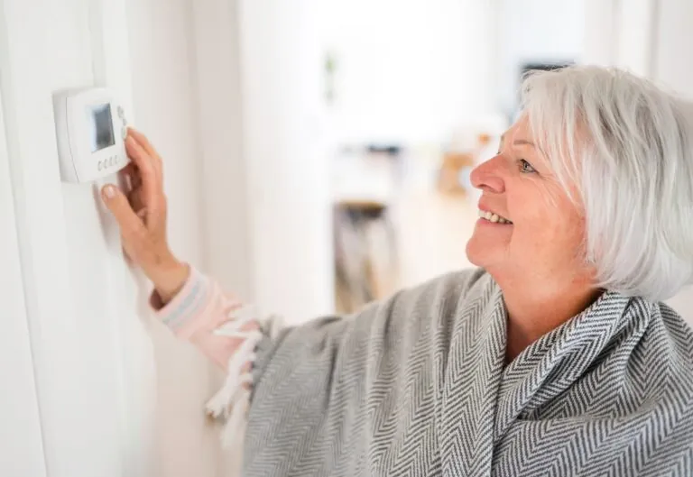 A Senior woman adjusting her thermostat at home