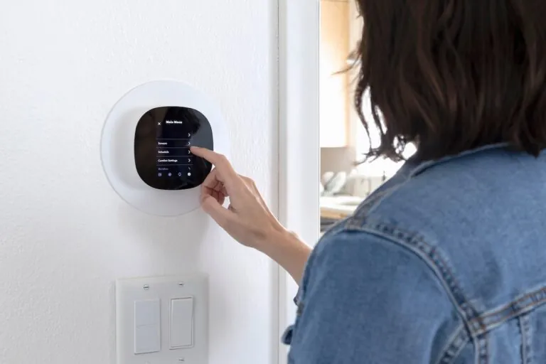 Adjusting the AC thermostat. Woman looking at smart thermostat menu