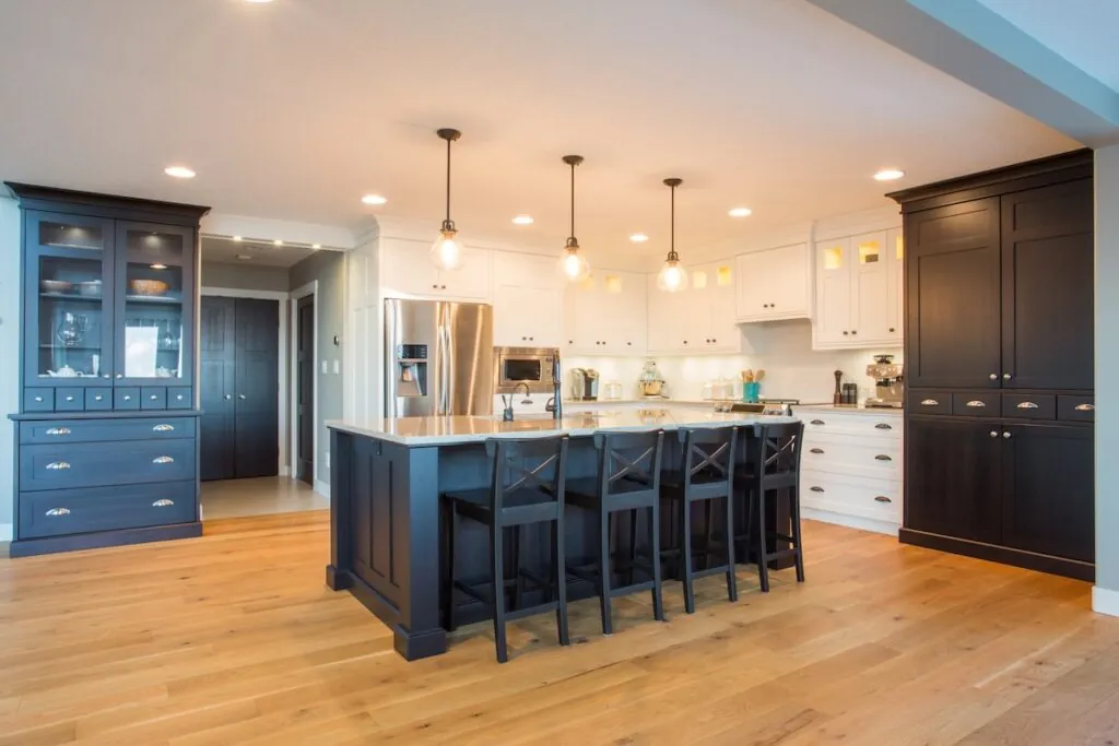 Custom kitchen with built in appliances, hard wood floors, and light and dark cabinetry, lights on
