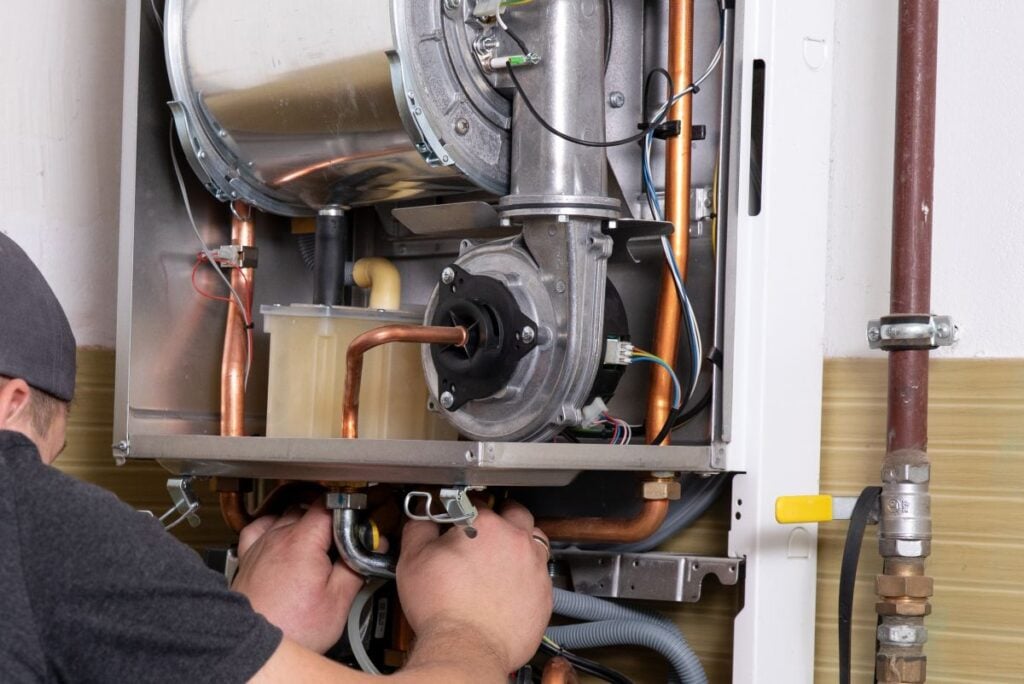 plumber fixing central heating system, Worker servicing a gas boiler