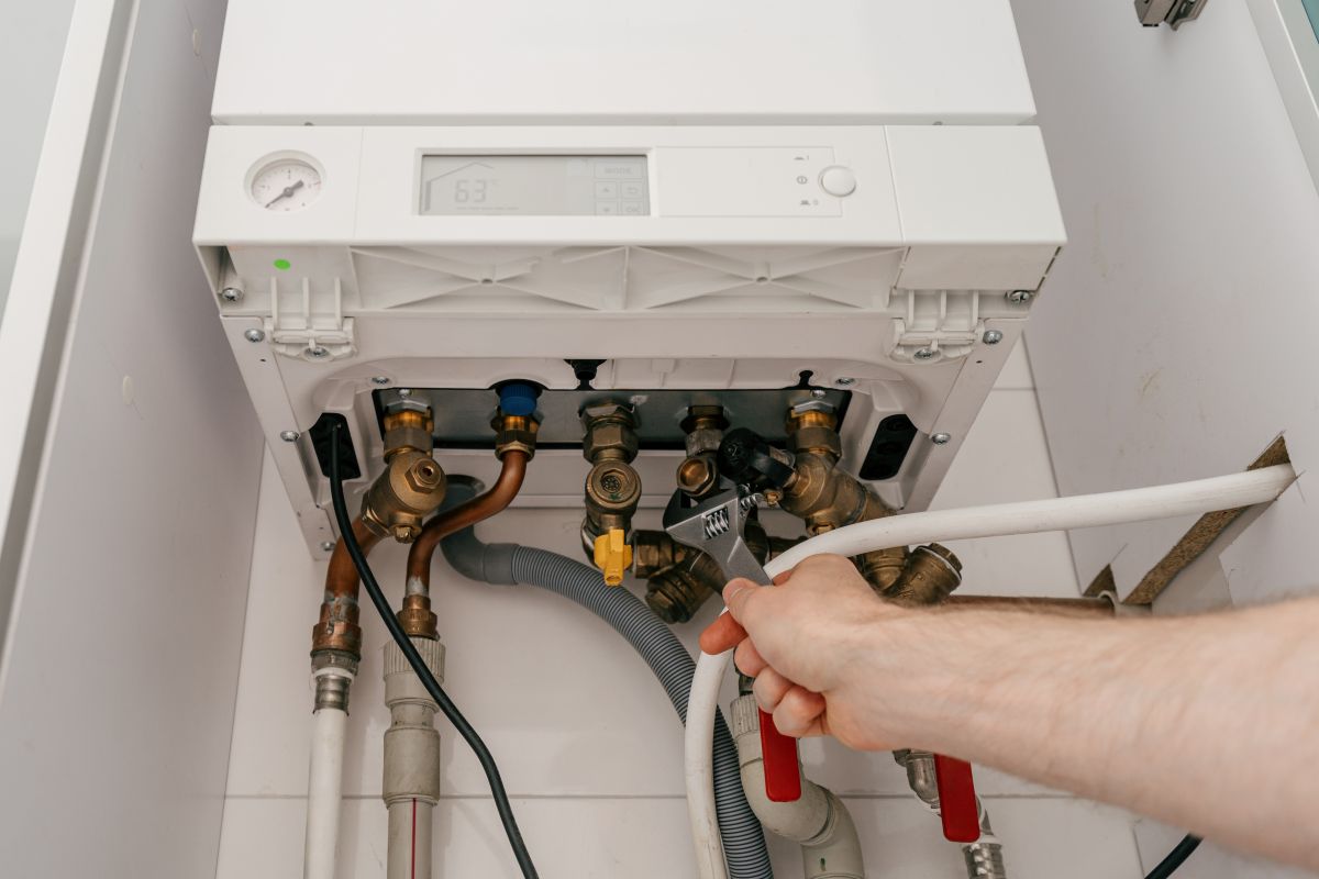 Repairman fixing modern gas boiler in utility room for efficient heating