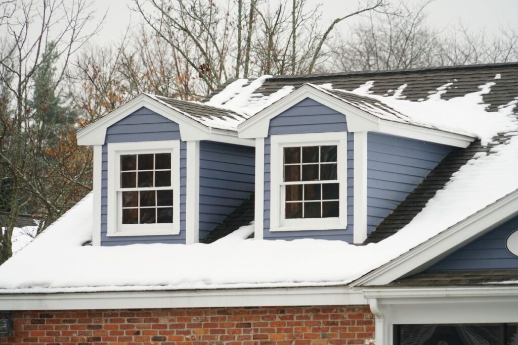 brick house with shingle roof covered in snow